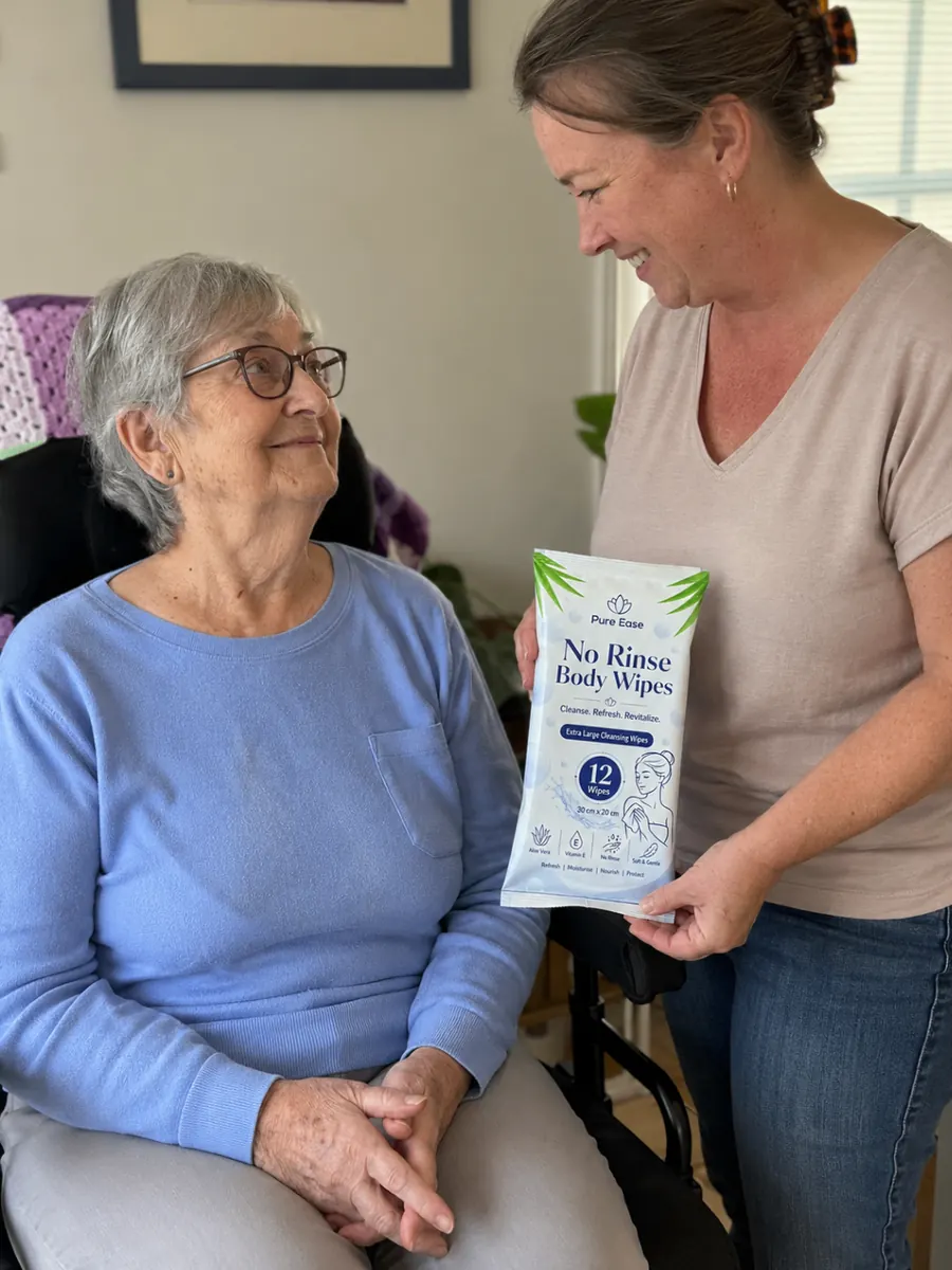 Carer showing PureEase No Rinse Body Wipes to an older woman seated at home.